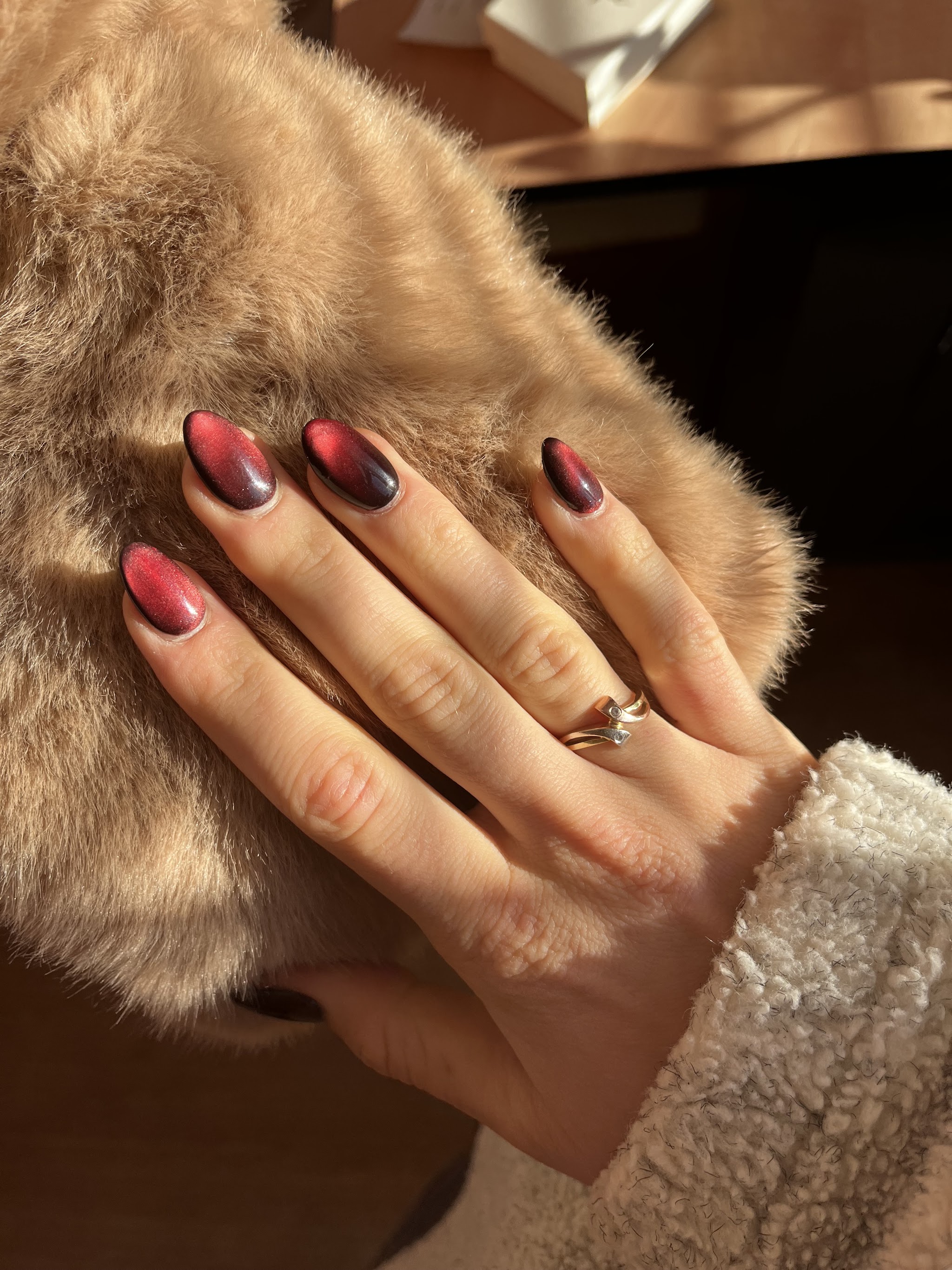Donkerrode cat-eye nagels op een bontmuts, foto van Veronique Bogouslavskii